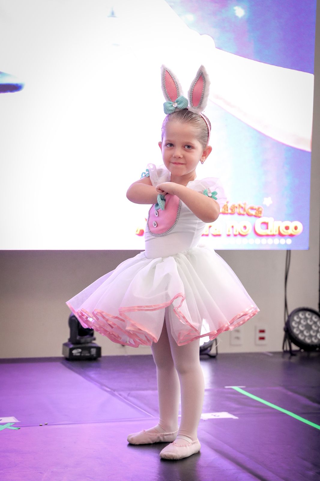 Pequena bailarina com orelhas de coelhinho e tutu branco no palco