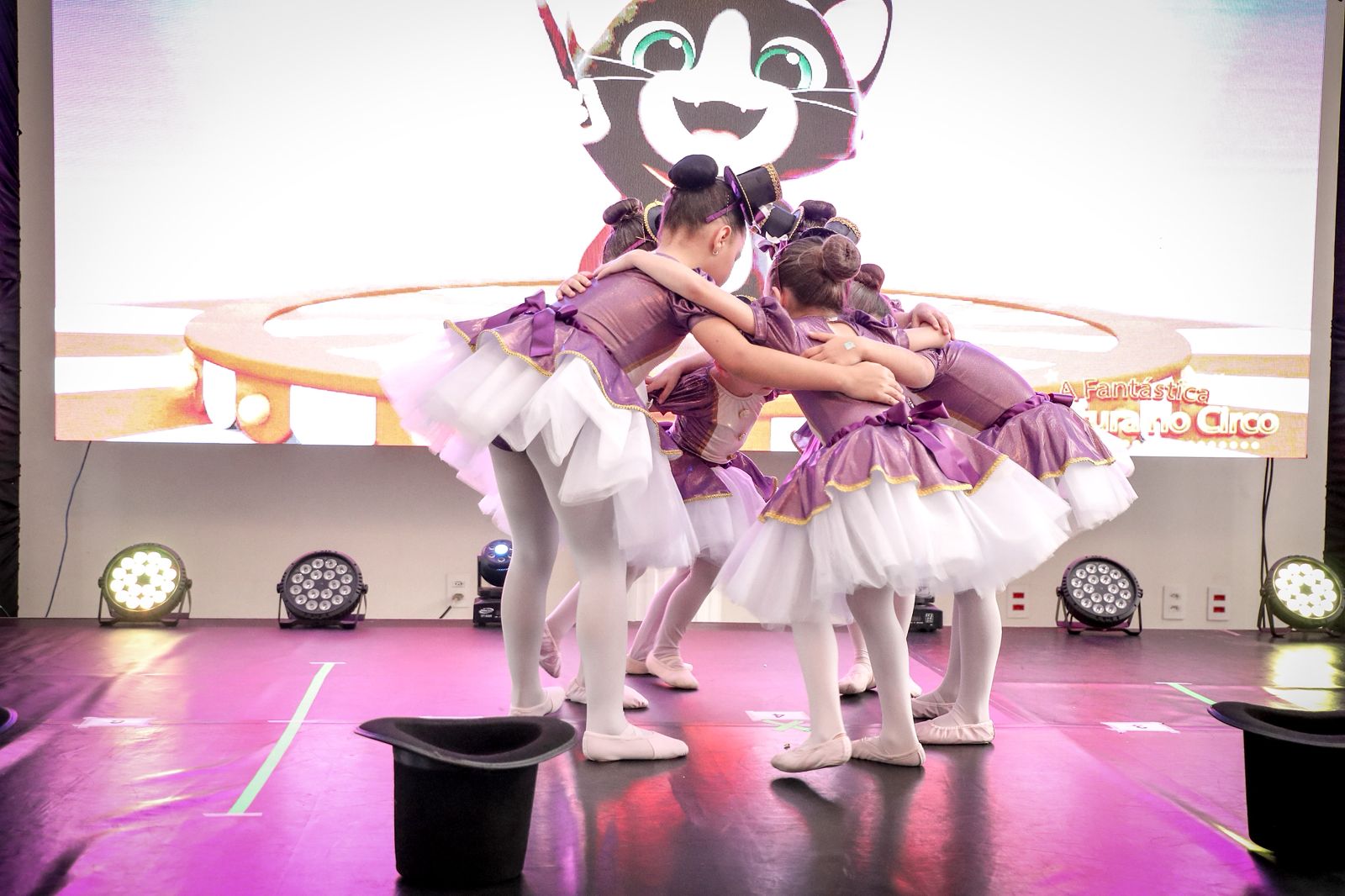 Bailarinas abraçadas em grupo com figurinos lilás