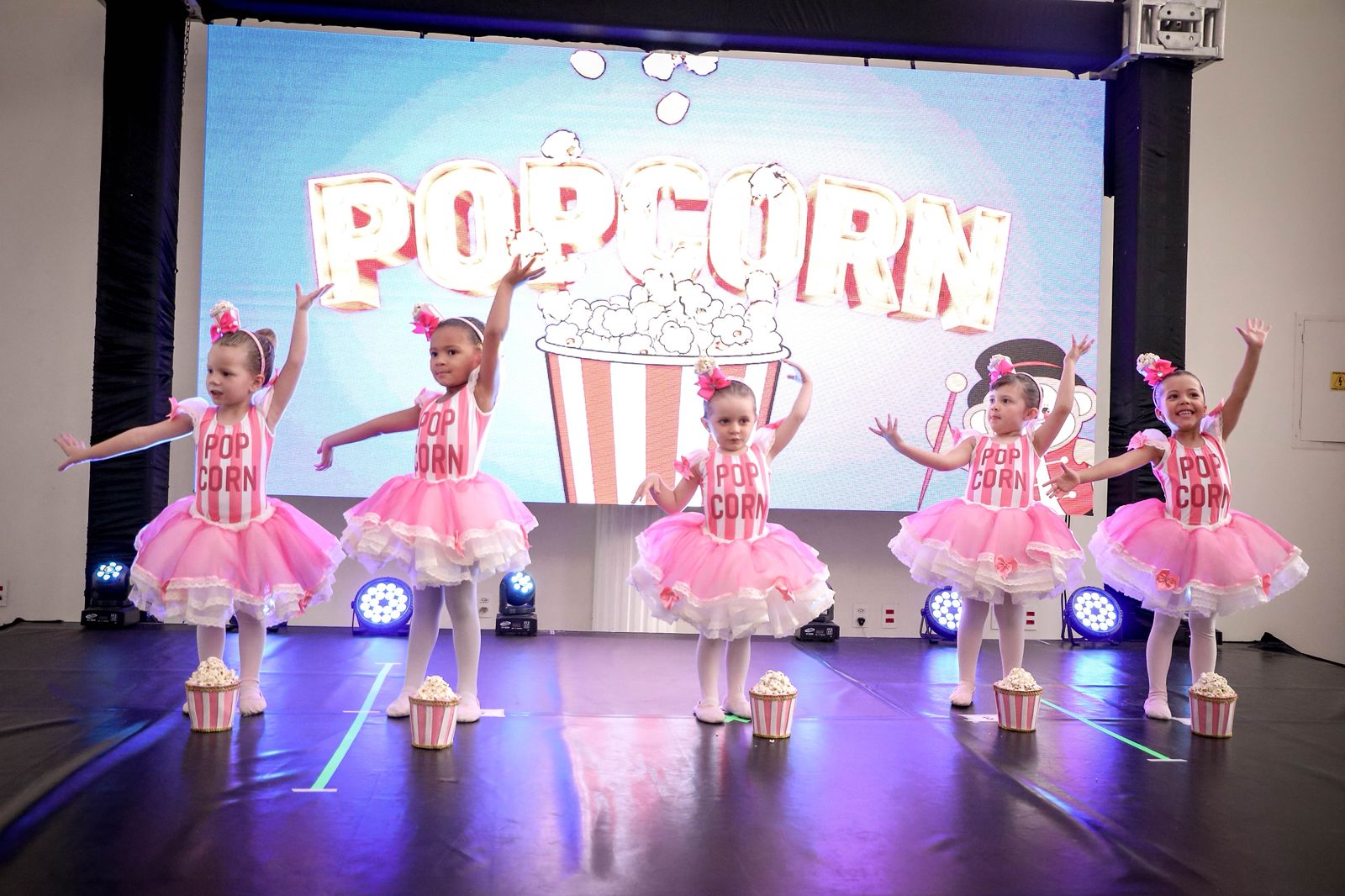 Cinco bailarinas em figurino de pipoca cor-de-rosa, dançando juntas no palco
